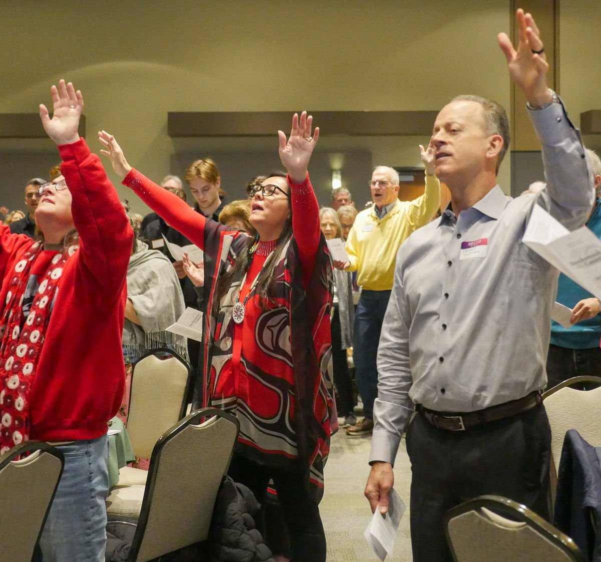Attendees worshipping with hands raised